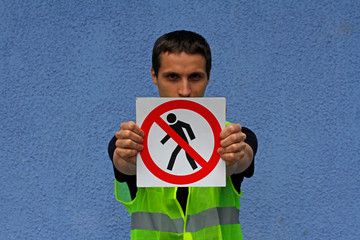 Man in a yellow waistcoat holding sign 