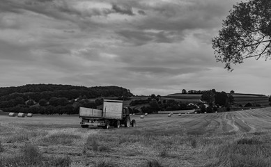 Fototapeta na wymiar Tractor with trailer on the wheat field, b&W photo
