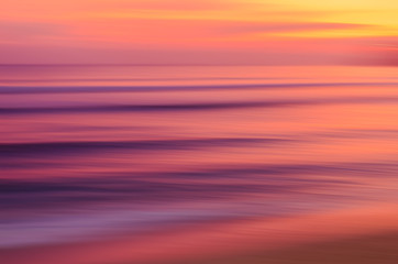 Motion blur tropical sunset beach with bokeh sun light wave abstract background.