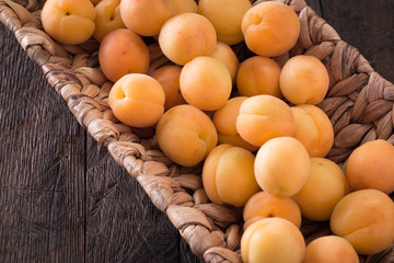 Delicious ripe apricots in a wooden bowl on the table close-up.