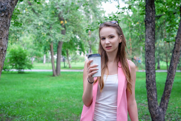 Beautiful happy young woman drinking coffee in park