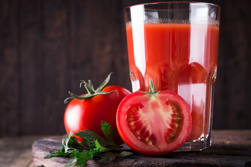 Glass of tomato juice with vegetables on wooden background