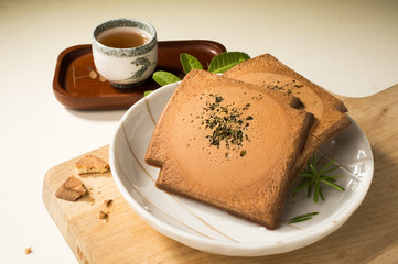Square cookies with cup of tea, Chinese pancakes.