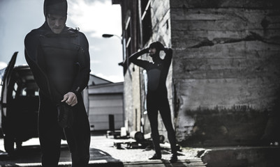 Two surfers taking off wetsuits and surfing gear