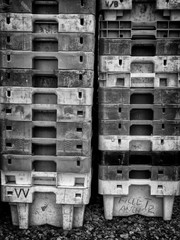 Empty plastic fishing crates stacked up on a beach