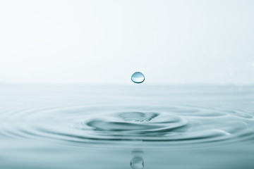 Water drop and splash on water surface on blue background