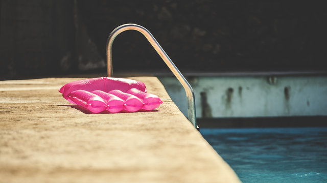A pool raft balanced on the side of a swimming pool.