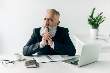 thoughtful senior businessman at workplace in modern office