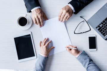 top view of business partners signing contract during meeting