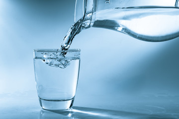 Drinking water is poured into a glass from a jug