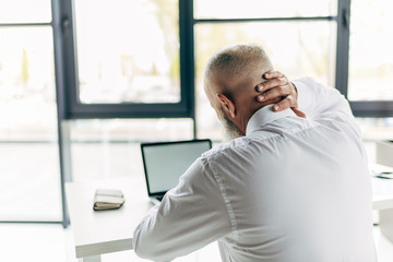 Fototapeta premium senior businessman with pain in neck working with laptop