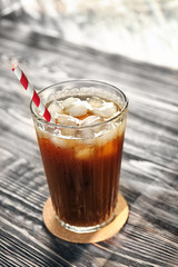 Glass with cold brew coffee and stand on wooden table