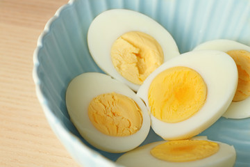 Sliced hard boiled eggs in ceramic bowl, closeup. Nutrition concept