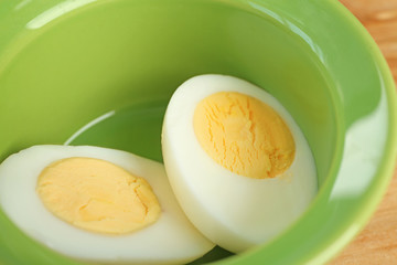 Sliced hard boiled egg in ceramic bowl, closeup. Nutrition concept