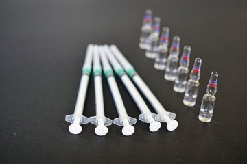 Ampoules and syringes on black background. Selective focus