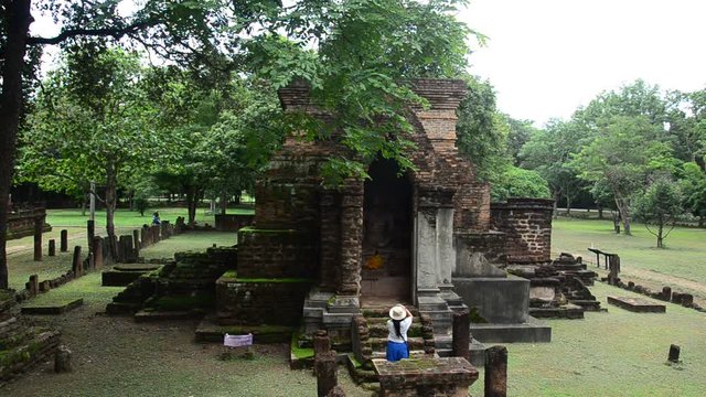 Travelers thai woman walking and visit ancient building and ruins of Kamphaeng Phet Historical Park is an archeological site and Aranyik Area in Kamphaeng Phet, Thailand