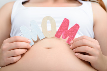 cropped view of pregnant woman holding mom word on her belly