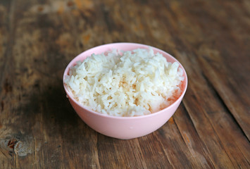 jasmine rice in pink bowl on wooden table.