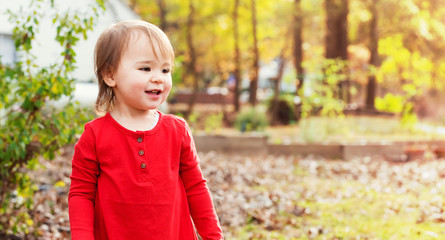Happy toddler girl playing outside in autumn 
