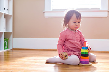Happy toddler girl playing with her toys in her house
