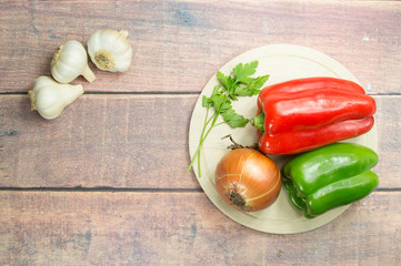 garlic on the left and peppers, onion and parsley on the right on the table