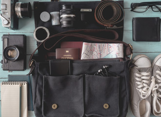 travel concept, Outfit of traveler with retro camera film, vintage bag, notebook, passport, glasses, sneaker, Belt, smartphone on wooden background, vintage tone style