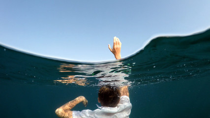 young man sinking into the sea