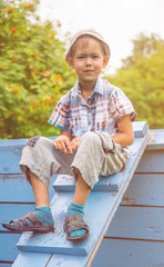 the boy,six years old , sitting on the wooden stairs for sports games