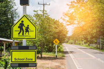 Yellow sign school zone symbol in the countryside . - 166218166