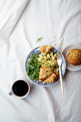 Breakfast in bed. Scrambled eggs with cheese croissants, raspberry muffin and black coffee. Morning treat concept. Composition with copy space.