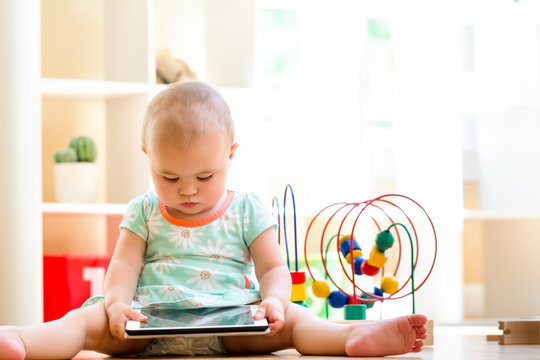 Toddler girl watching a tablet computer in her house