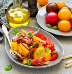 Vegetarian salad with fresh tomato, with red onion, basil and olive oil.