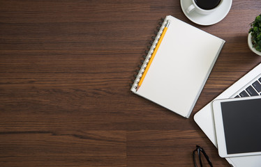 Wood office desk table with laptop computer, notebook with pen and cup of coffee.Top view