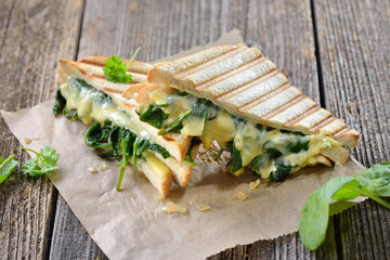Im Kontaktgrill gepresstes italienisches Panini mit jungem Blattspinat, Zwiebeln  und Käse -...