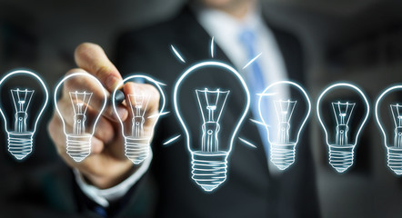 Businessman drawing a sketch lightbulb with a pen
