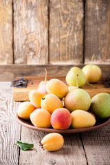 Ripe organic apricots and pears on rustic wooden table