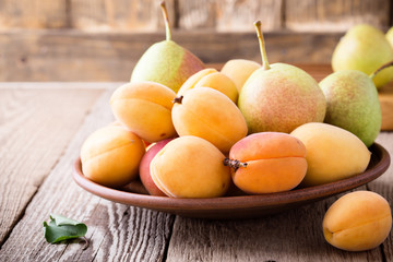 Naklejka na ściany i meble Ripe organic apricots and pears on rustic wooden table