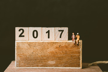 Miniature people, businesswoman sitting on wooden number block using for business and counting End of Year and Happy New year day Celebration concept