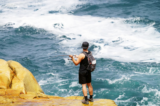 angler fisherman  fishing in rocks of cliff