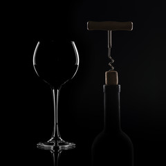Red wine pouring in wineglass from bottle over black background. Wine list design menu with copyspace. Alcohol beverage card backdrop.
