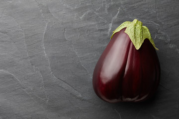 Fresh ripe bell shaped eggplant on dark stone background, top view