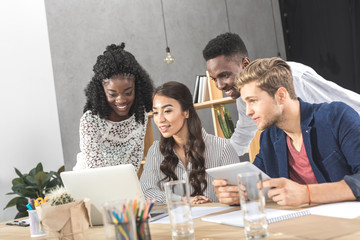 multicultural concentrated business colleagues using laptop together at workplace in office