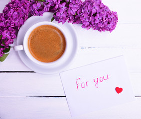 Cup of black coffee and a saucer and white paper envelope