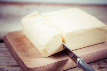 Butter on a wooden chopping board  cut with a knife