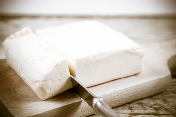 Butter on a wooden chopping board  cut with a knife