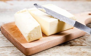 Butter on a wooden chopping board  cut with a knife