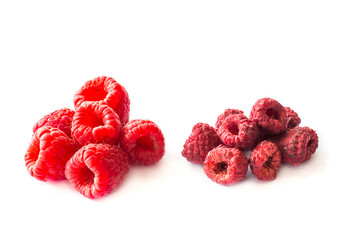 Freeze dried and fresh raspberries on a white background.