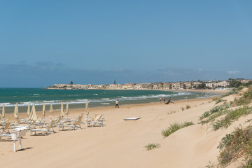 Fototapeta na wymiar Feiner Sandstrand mit Sonnenschirmen und Liegen an einer Badebucht am Mittelmeer