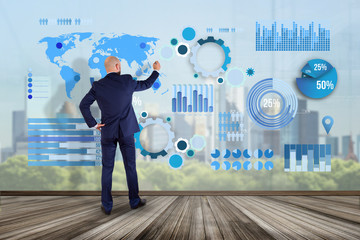 Businessman in front of a wall writing on a business graph and chart interface - business concept