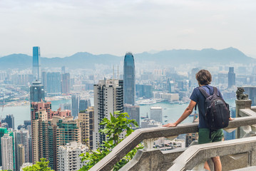 Panorama of Young man traveler at the peak of Victoria against the backdrop of Hong Kong